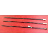 Three similar black lacquered walking canes with tapered shafts and applied silver cap handle