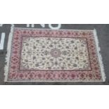 A fabric carpet, decorated with repeating foliate designs, on a cream coloured ground with a