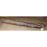 An African hardwood walking stick, having a loop handle, the shaft carved with native masks and