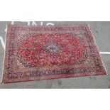 A Persian carpet, profusely decorated with floral designs in bright colours, on a red ground  120" x