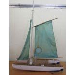 A painted wooden catamaran style pond yacht with a sail  24"L