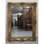 A late 19thC carved giltwood and gesso frame, decorated with foliate scrolls and flora, set with a