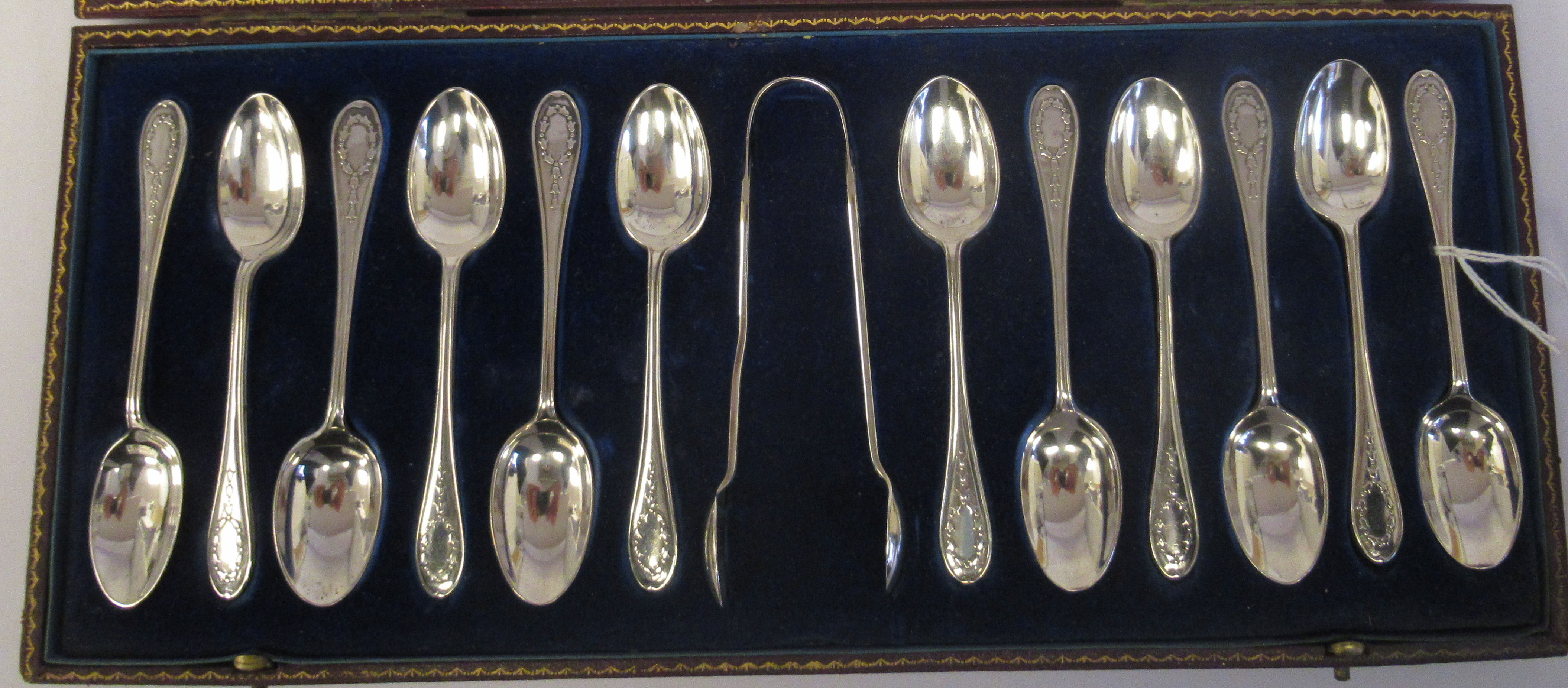 A set of twelve silver teaspoons and a pair of matching sugar tongs with cast bellflower ornament