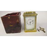 An early 20thC brass cased carriage clock with bevelled glass panels and a folding top handle, on