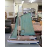 A painted wooden catamaran pond yacht with a sail  24"L