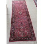 A Persian runner, decorated with floral motifs, on a red ground  106" x 33"