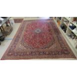 A Keshan carpet, profusely decorated with floral designs in bright colours, on a red ground  120"