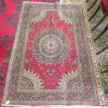 A Persian rug, decorated with a central starburst design medallion, bordered by floral designs, on a