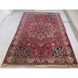 A Persian carpet, profusely decorated with flora and other designs, on a multi-coloured and red