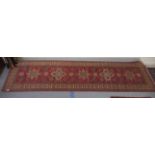 An Afghan Kazak runner, decorated with repeating central stylised decoration, on a red and multi-