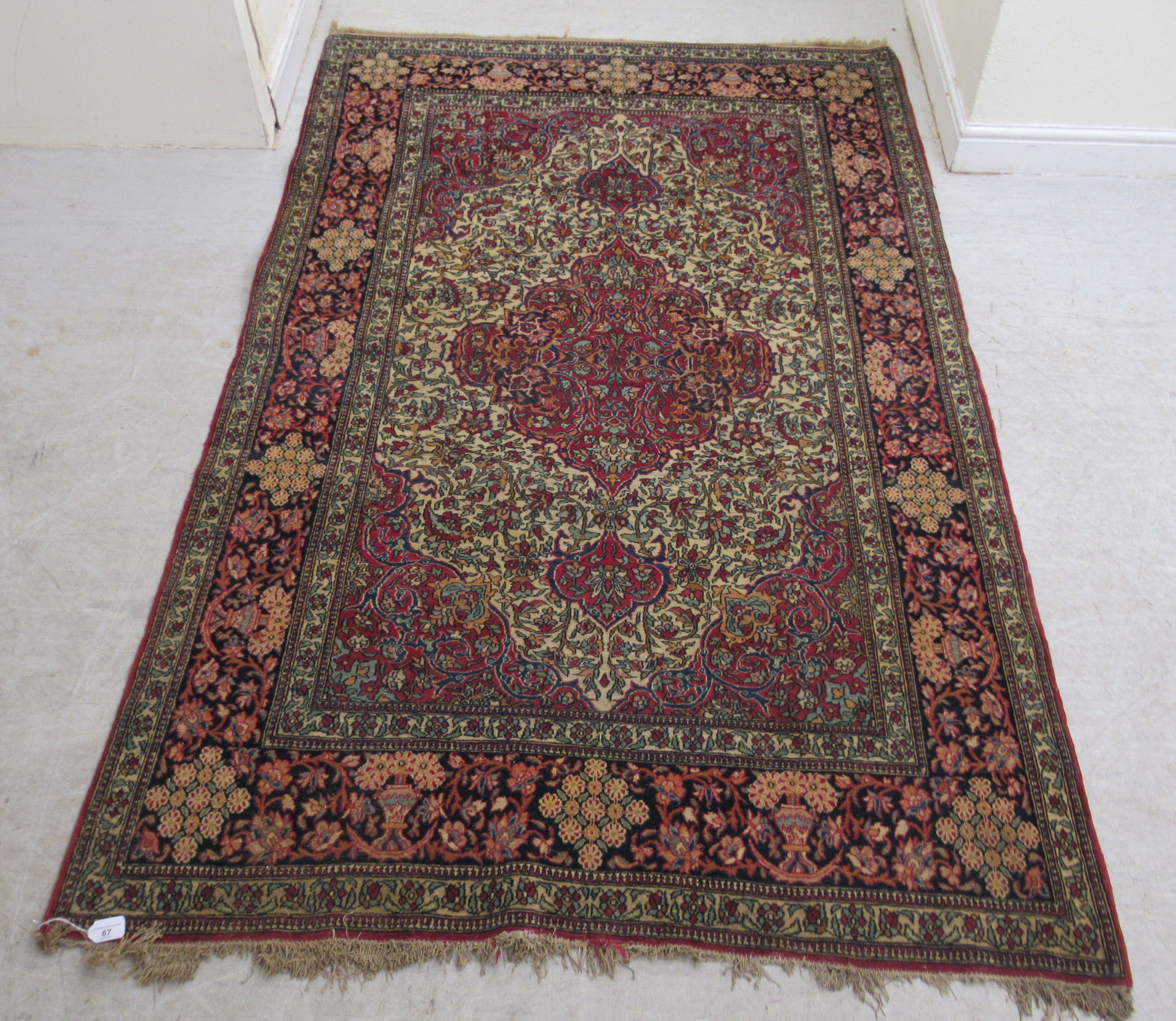 A Persian rug, decorated with a serpentine outlined medallion, bordered by stylised designs on a