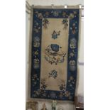 A 1950/60s Chinese woollen rug, decorated with birds and flora with a blue border, on a cream ground