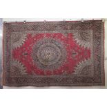 A Persian rug, decorated with a central starburst design medallion, bordered by floral designs, on a