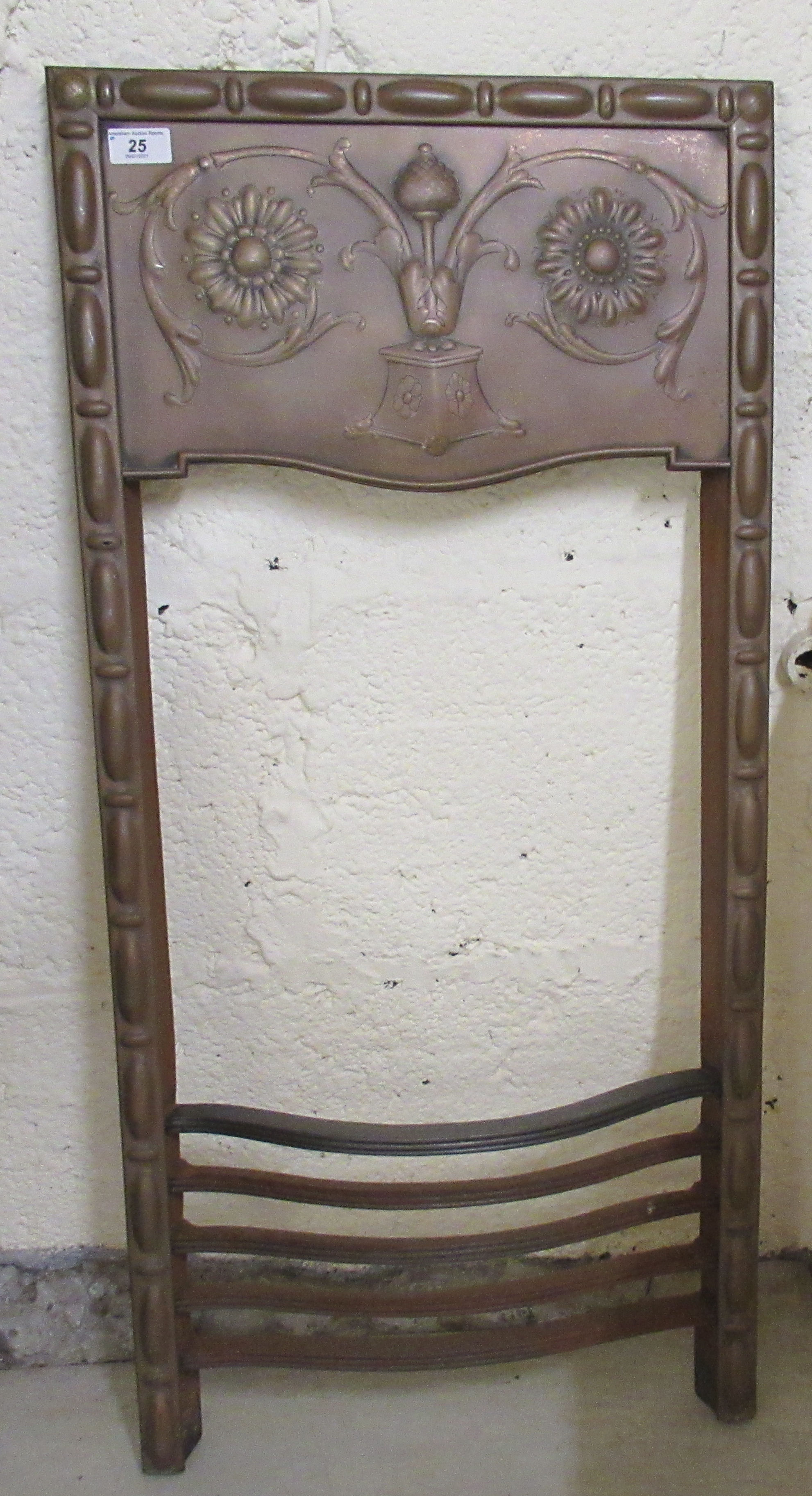 An Art Nouveau floral embossed copper front and cast iron fire grate with a five bar serpentine