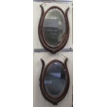 A pair of mid Victorian oval mirrors, set between pivoting mahogany horns and horse haim design