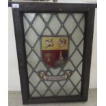 An early 20thC oak framed lead glazed window panel, decorated with a shield armorial crest '