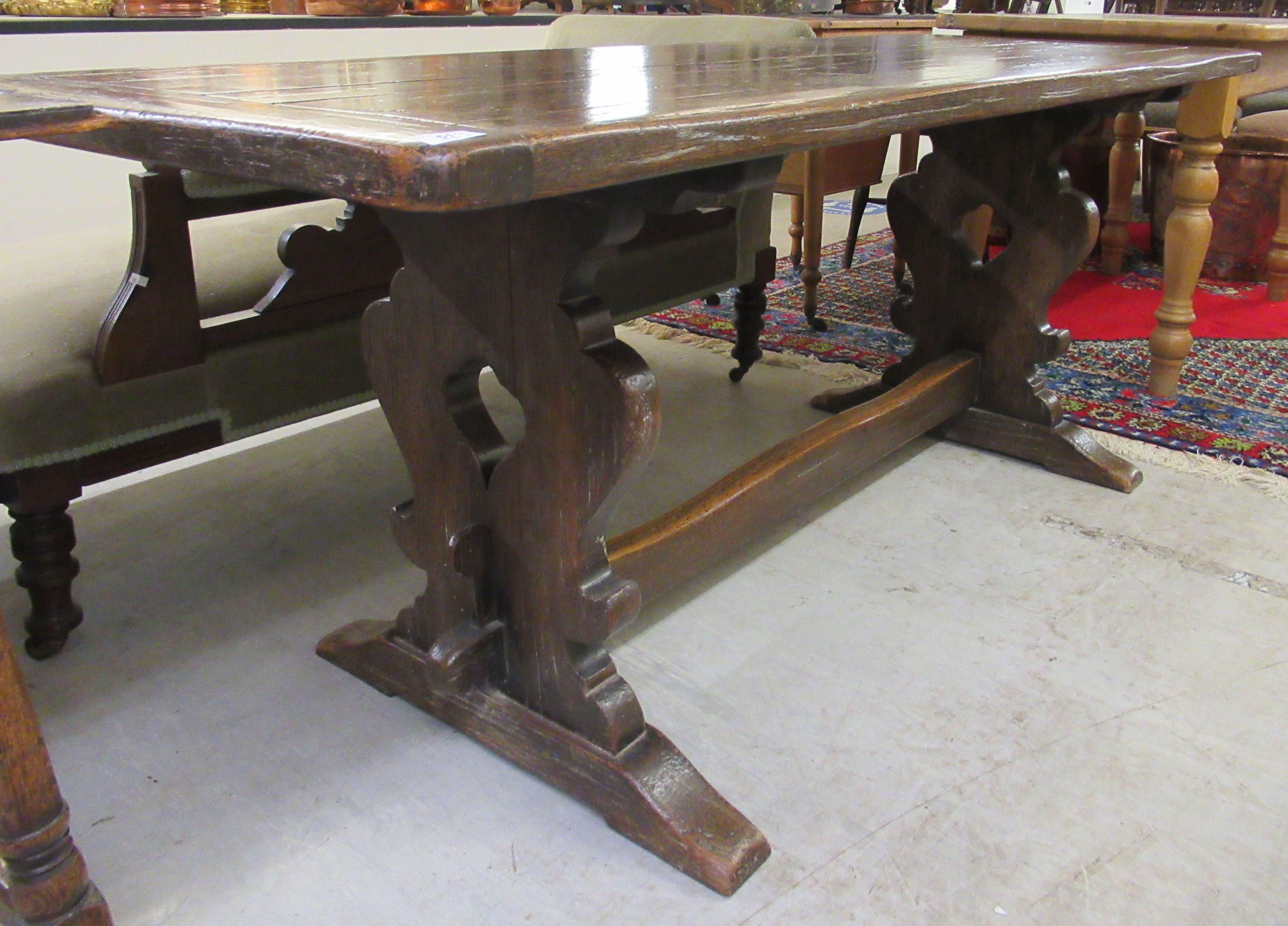 A late 19thC Jacobean design oak refectory table, raised on opposing vase shaped ends and platform