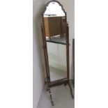 A 1930s Queen Anne style walnut framed cheval mirror, the shaped plate set within pivoting horns,