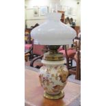 An Edwardian china and brass mounted oil lamp, decorated with autumnal leaves and a milk glass shade