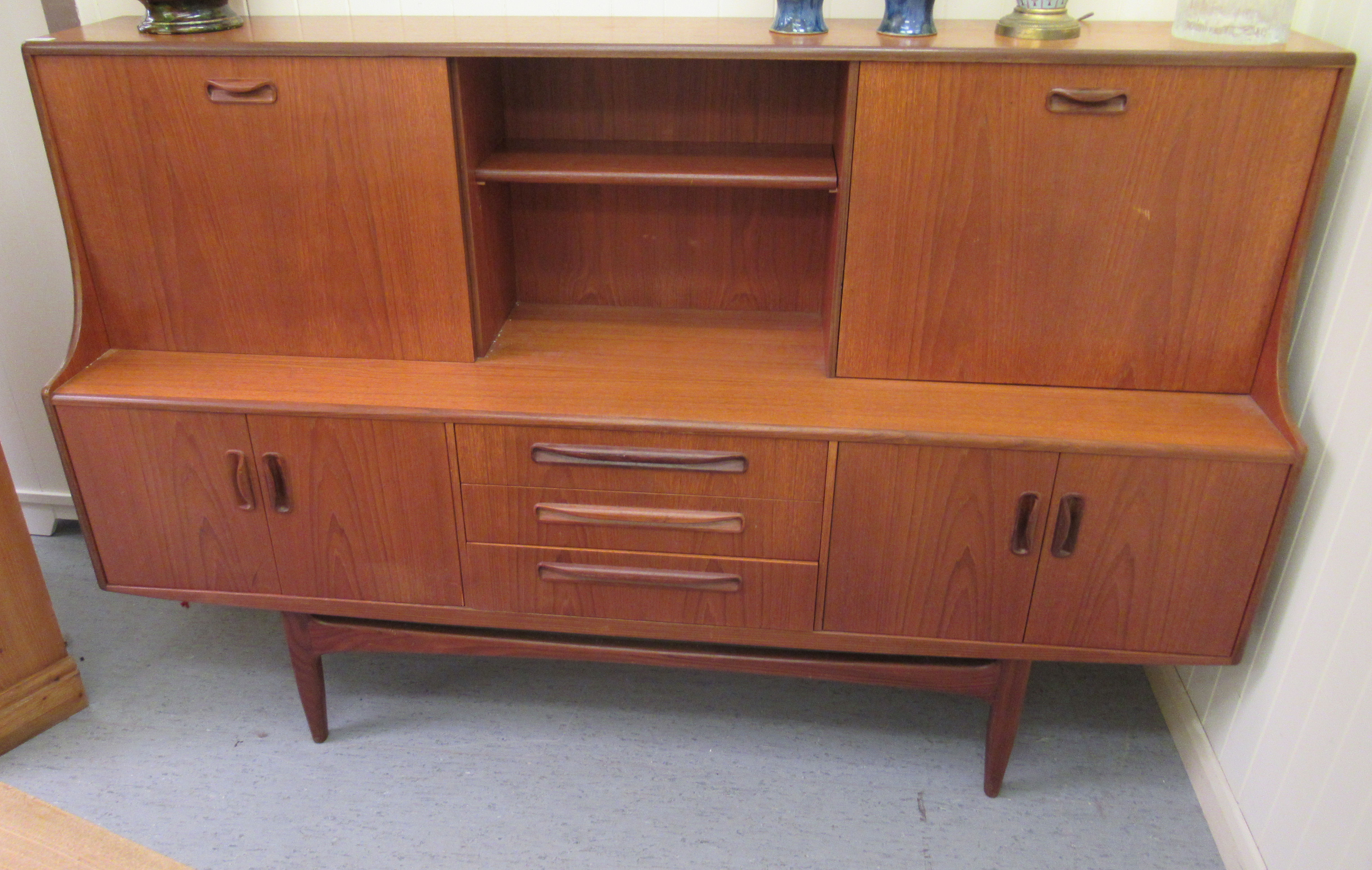 A G-Plan teak living room unit with an arrangement of sliding doors, open shelves, a fall flap