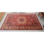 A Sarouk rug, decorated with a central motif, bordered by stylised designs, on a red ground  66" x