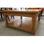 A modern light oak coffee table, raised on ring turned block legs, united by a planked undershelf