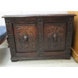 A late Victorian oak coffer with a hinged lid, over a twin panelled front and carved mask motifs, on