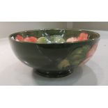 A Moorcroft pottery footed bowl, decorated in the Hibiscus pattern, on a green ground  6.5''dia