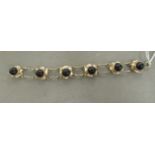 An Arts & Crafts inspired silver gilt bracelet with multiple links, each set with a cabochon cut