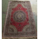 A Persian rug, decorated with a central starburst design medallion, bordered by floral designs, on a