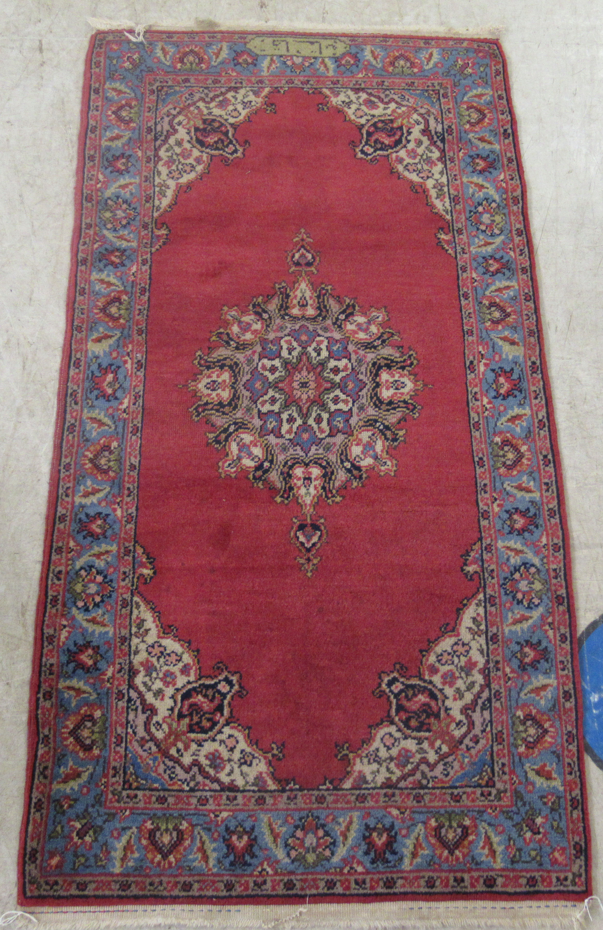 A Tabriz rug, decorated with a central medallion, bordered by floral designs, on a red ground