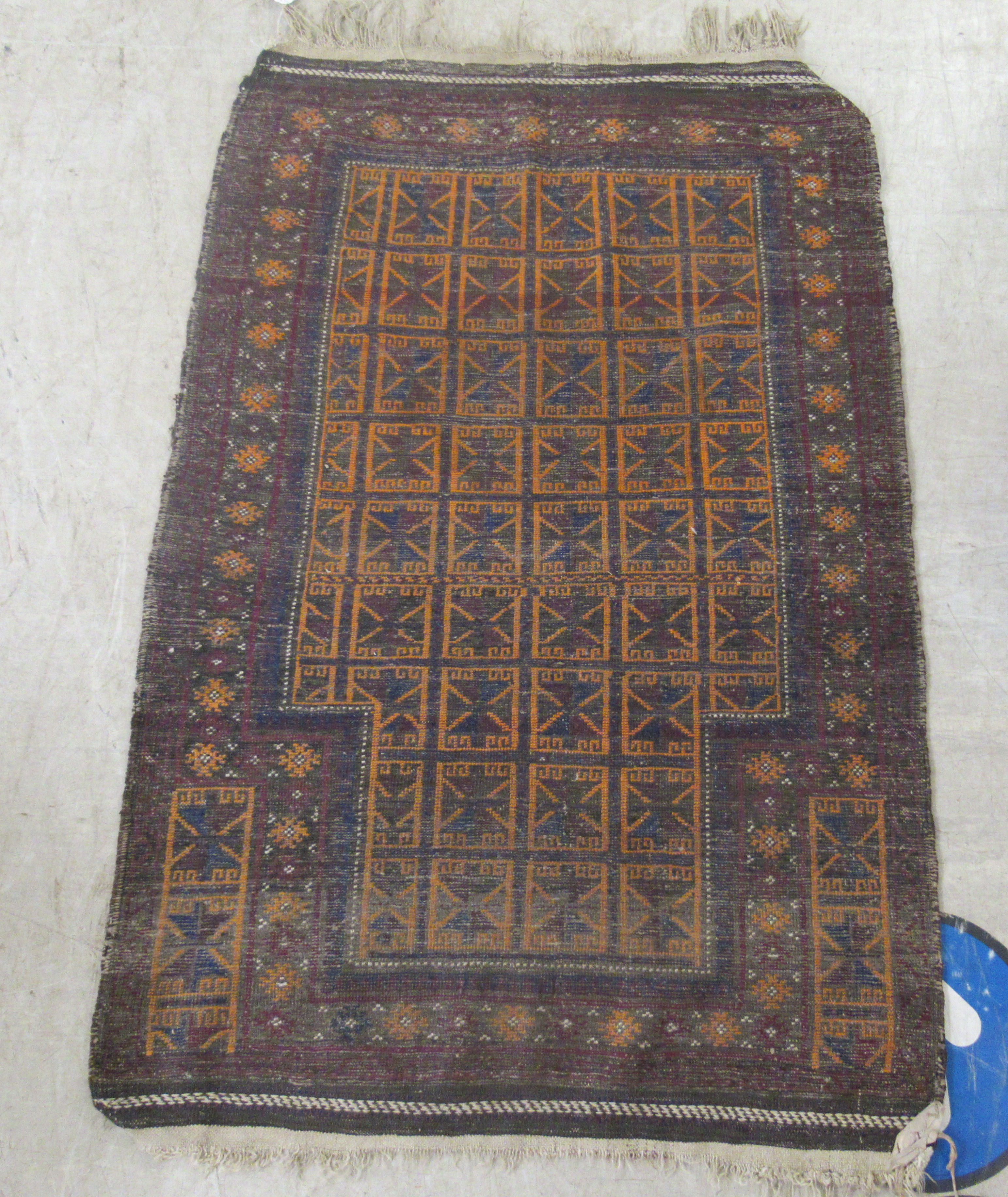 A Baluchistan rug, decorated with repeating stylised designs, on a brown ground  35'' x 42''