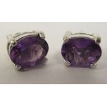 A pair of silver coloured metal claw set amethyst earrings
