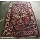 A Sarouk rug, decorated with a central motif, bordered by stylised designs, on a red ground  66''