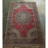 A Persian rug, decorated with a central starburst design medallion, bordered by floral designs, on a