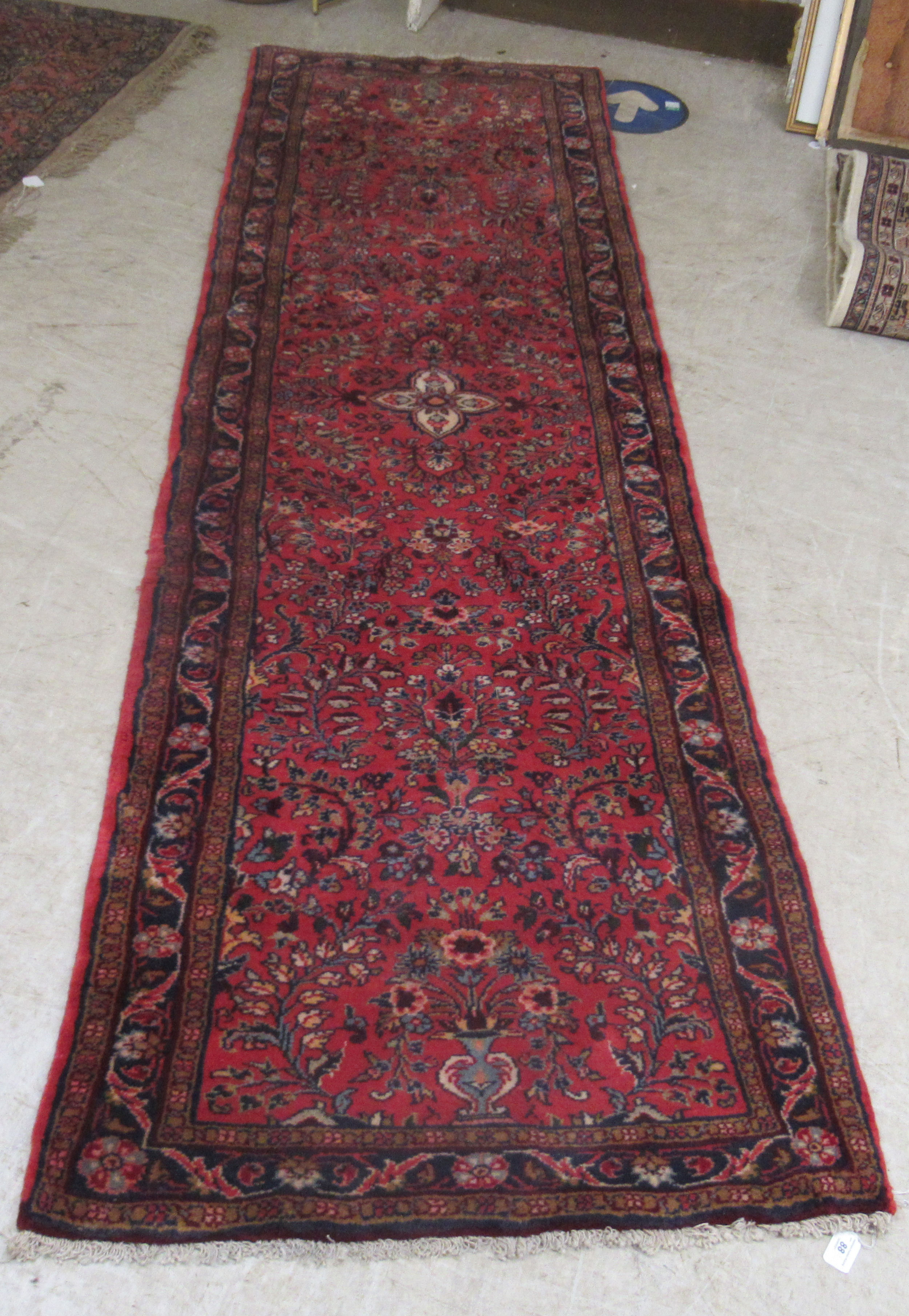 A Persian runner, decorated with floral motifs, on a red ground  106'' x 33''