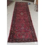 A Persian runner, decorated with floral motifs, on a red ground  106'' x 33''