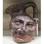 In the manner of Martinware, a ceramic double face jug with an angular handle  variously