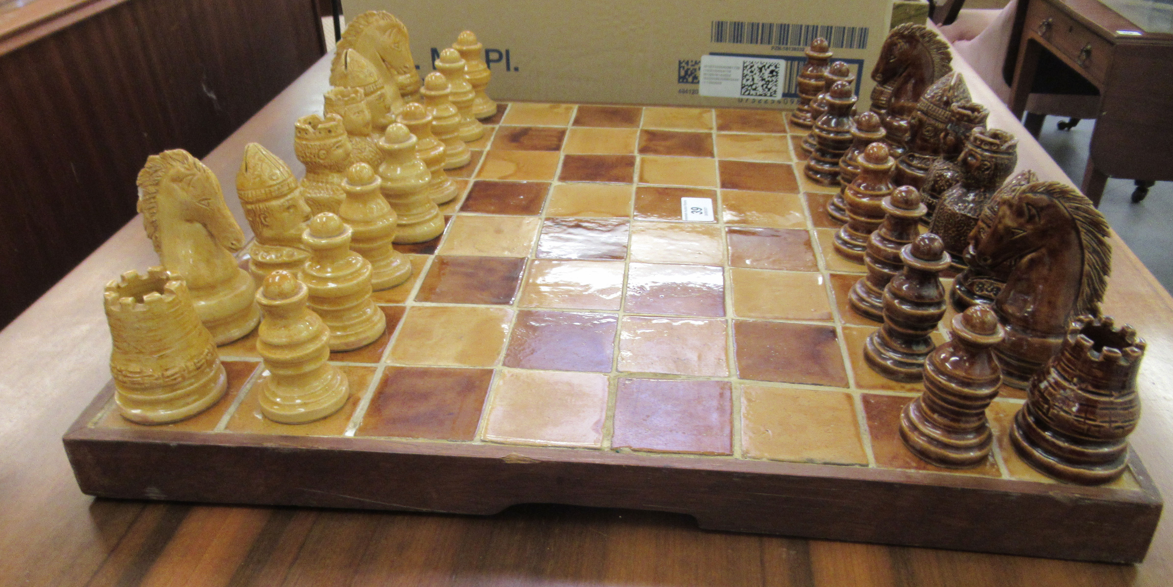 A modern ceramic, two tone tiled chessboard  20''sq with hollow pottery pieces  the kings 3.25''h