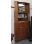 A mid 20thC two part, light oak finished corner unit with canted corners, comprising an