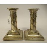 A pair of late Victorian loaded silver cylindrical candlesticks with floral embossed and bead