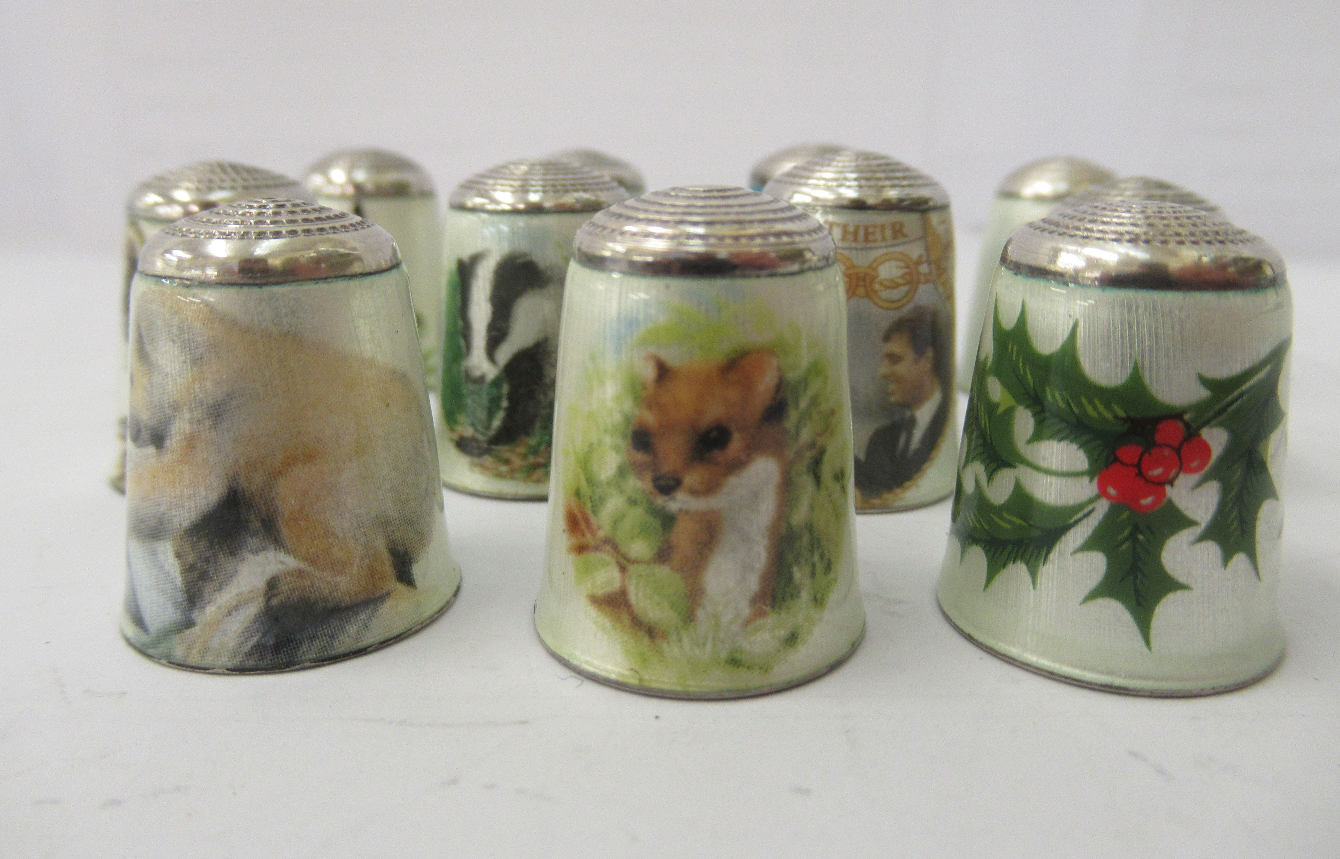 Eleven enamelled white metal thimbles, mostly decorated with wildlife