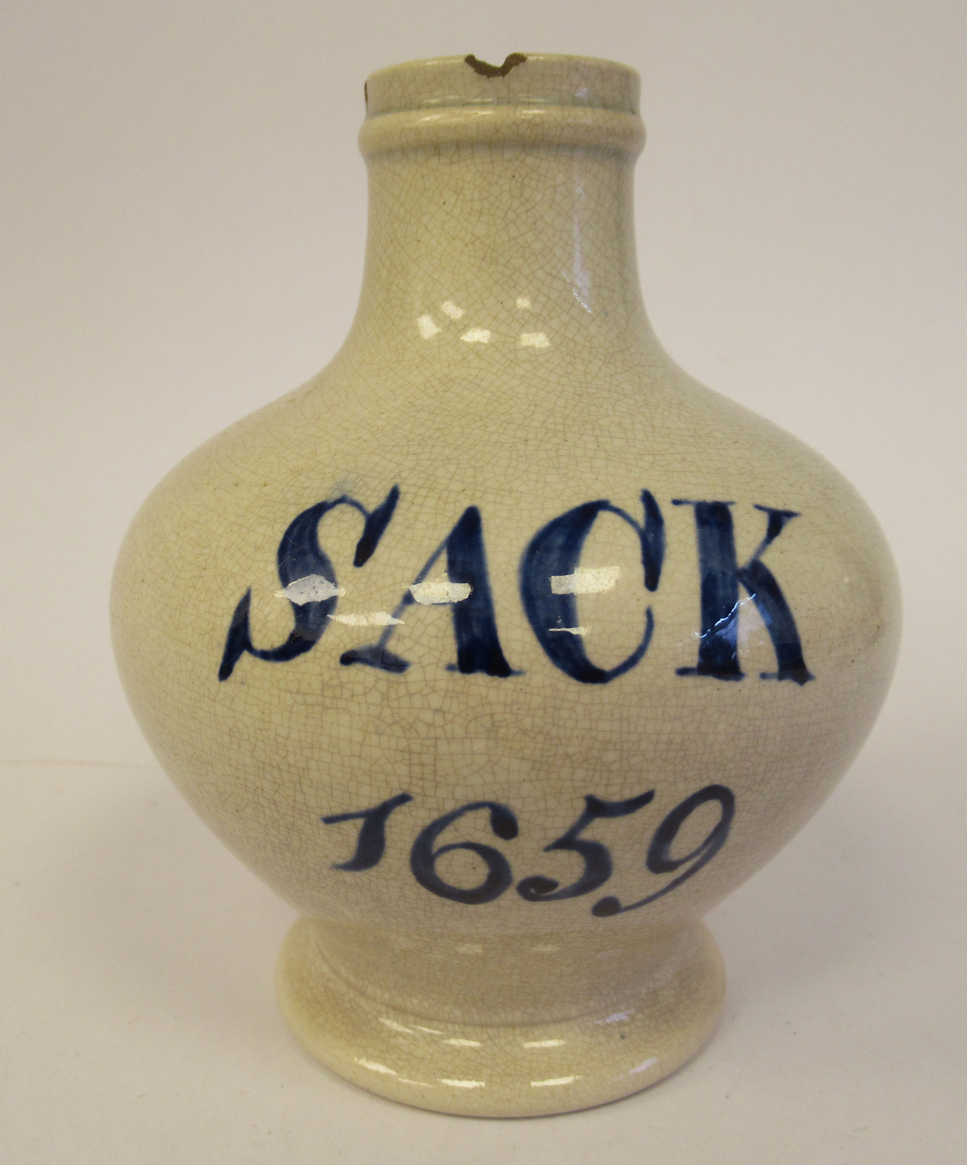 An early 19thC cream coloured Pearlware wine bottle of squat, bulbous form with a narrow neck and