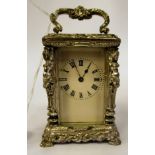 A lacquered, decoratively cast silver coloured metal cased miniature carriage timepiece