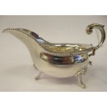 An Edwardian silver sauce boat with a flared gadrooned rim and a double C-scrolled handle,