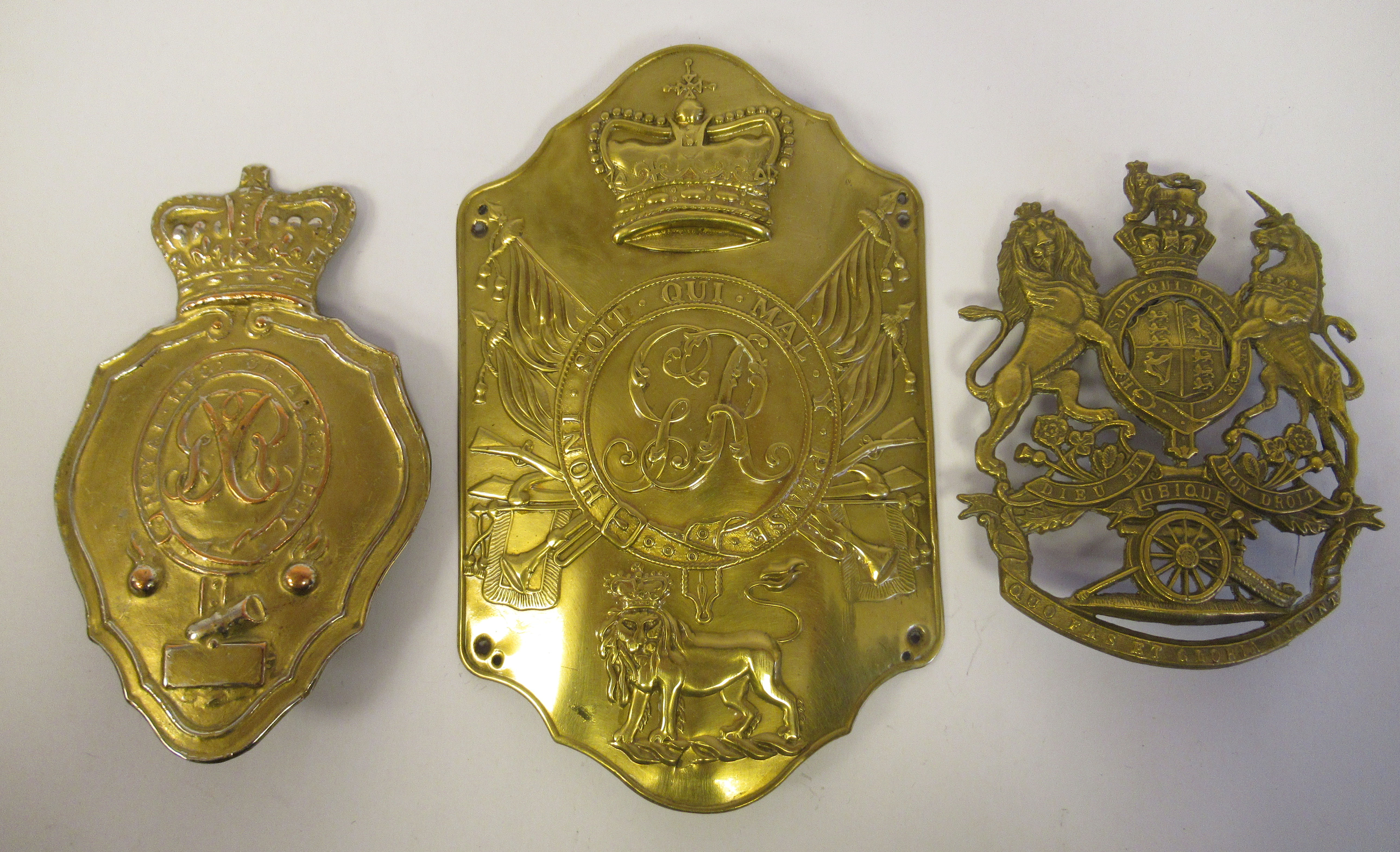 A Royal Artillery shako plate; a stove pipe shako plate; and a coat of arms helmet plate  (Please