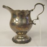 A George III silver cream jug of bulbous form with a decoratively cut, flared wavy rim and a