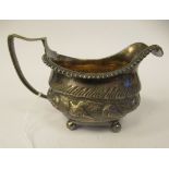 A George III silver cream jug of oval ogee form with a flared, gadrooned border and angular