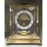 A Kundo Electronic lacquered brass cased mantel timepiece; the exposed battery powered movement