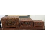 A graduated set of three modern Chinese camphorwood caskets with elongated carved ornament, raised